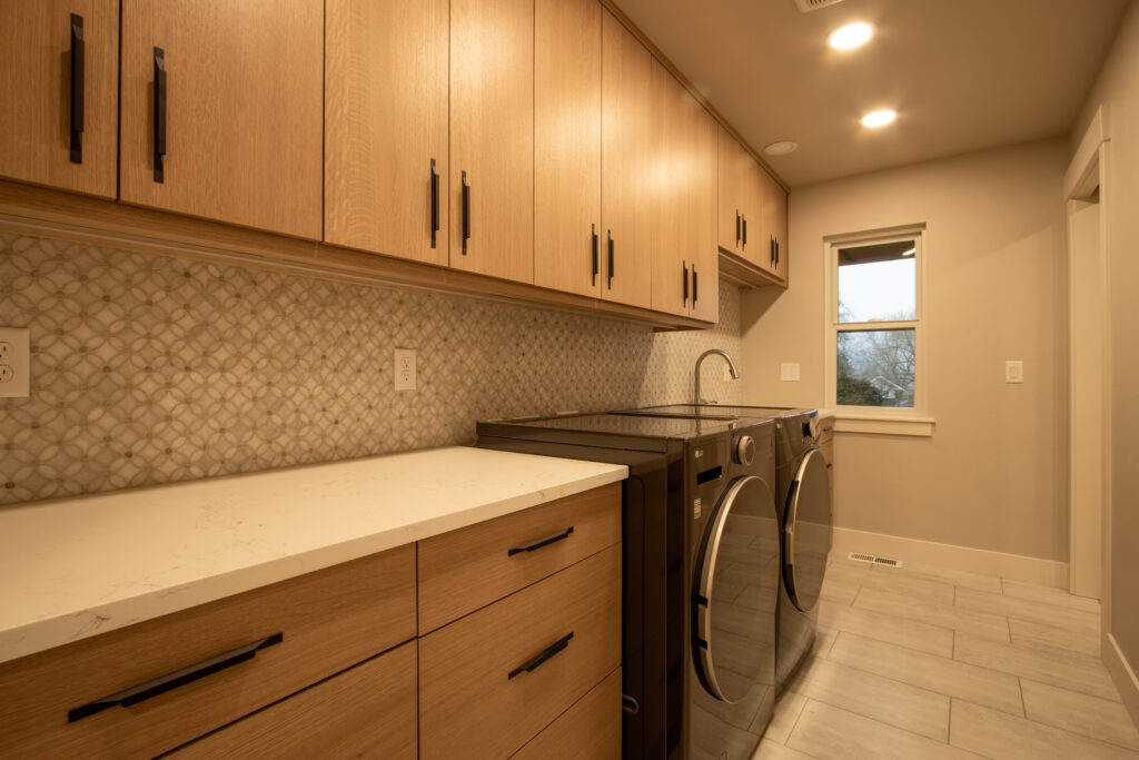 Floor-to-ceiling laundry cabinets with open utility shelving